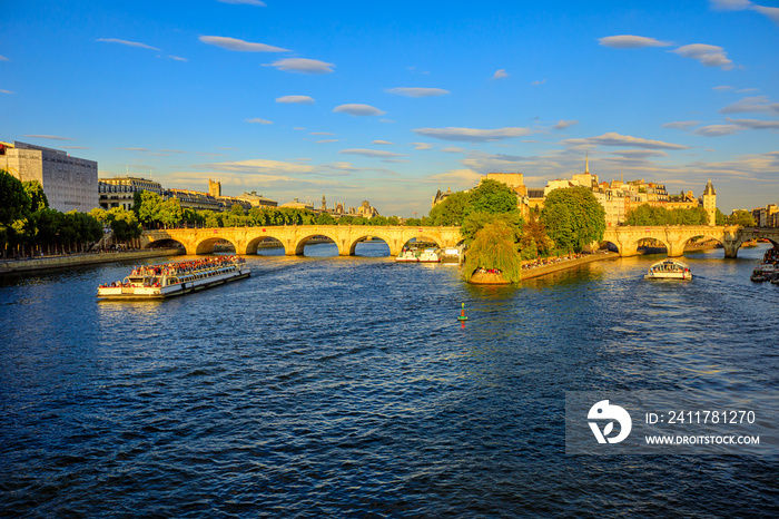 Tourist cruise on Seine river. Bateau mouche from Pont Neuf bridge and Notre Dame church on background. Tourist travelers in popular landmarks of Paris in France at sunset from Pont des Arts bridge.