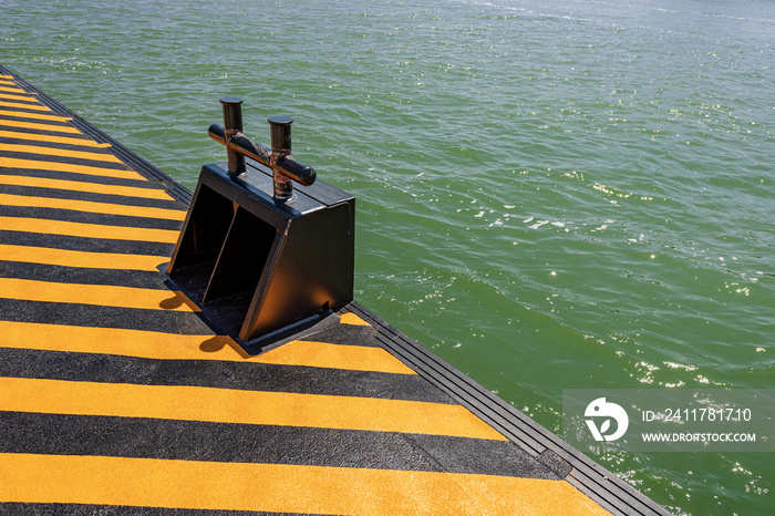 Close-up of an orange and black quay with a large metal mooring bollard for the ferry boats or vaporetto in the Venetian lagoon, Venice, Veneto, Italy, Europe.