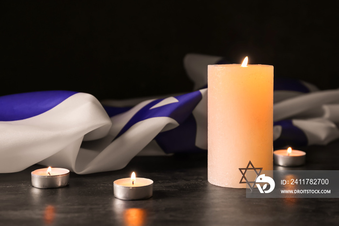 Burning candles and flag of Israel on dark background. Holocaust remembrance day