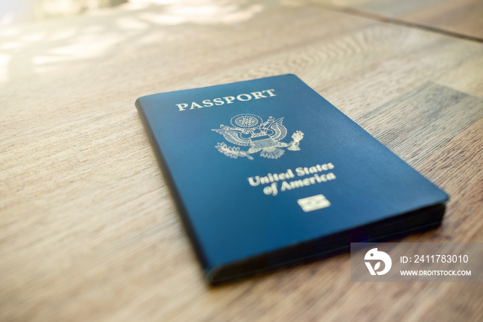 One single blue American passport laying on a wooden desk