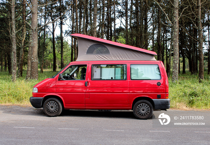 Red Van with roof up. Campervan parked next to forest.