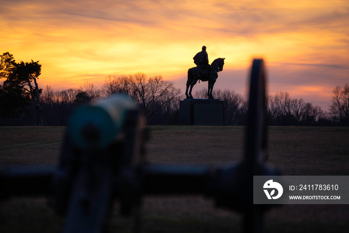 Sunset at Manassas National Battlefield Park from behind one of the canons and the silhouette of the Stonewall Jackson Monument.