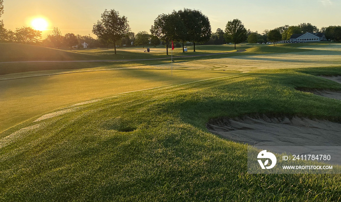 sunrise over golf course tee box green with red flag geese sand trap