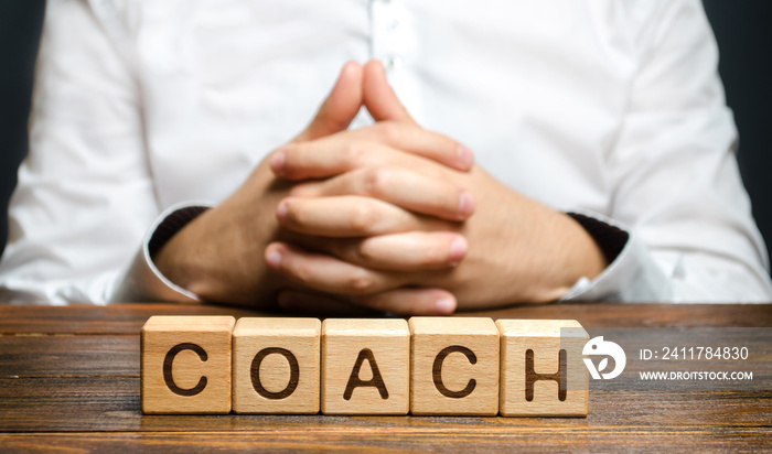 The inscription Coach and a man sitting with his hands clasped in a lock. Trainer and mentor. Self improvement. Achieving goals through training and guidance. Skills development