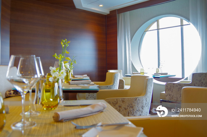 Formal elegant Suite Class restaurant dining room onboard luxury cruiseship or cruise ship liner with set tables, ocean views and impressive interior inside architecture