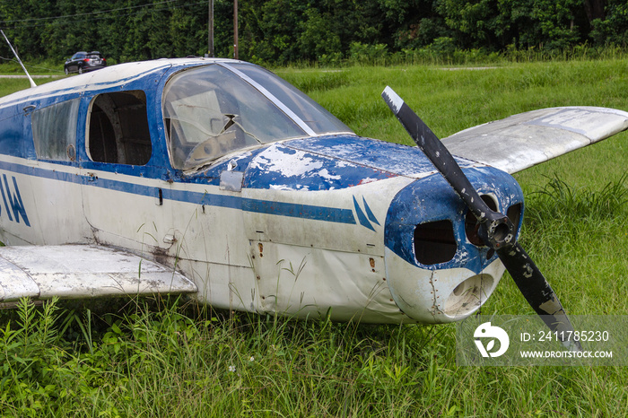 Close up of blue and white abandoned single prop plane left in grass