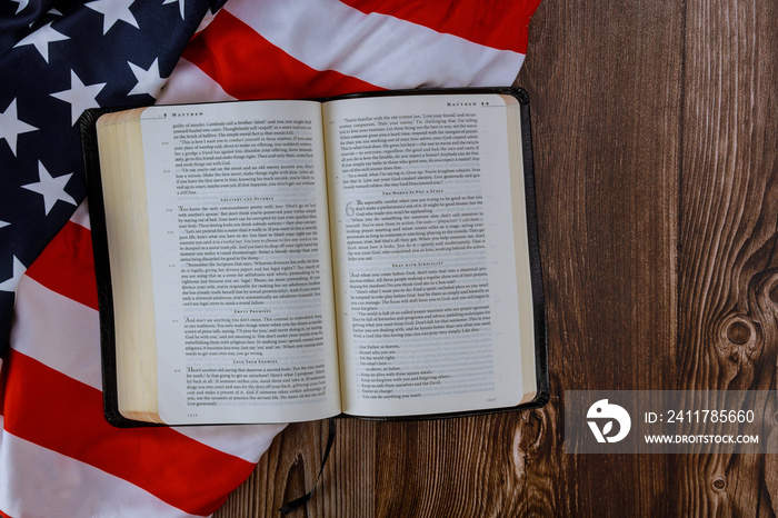 Open is reading Holy Bible book with prayer for america over ruffle American flag in wooden table