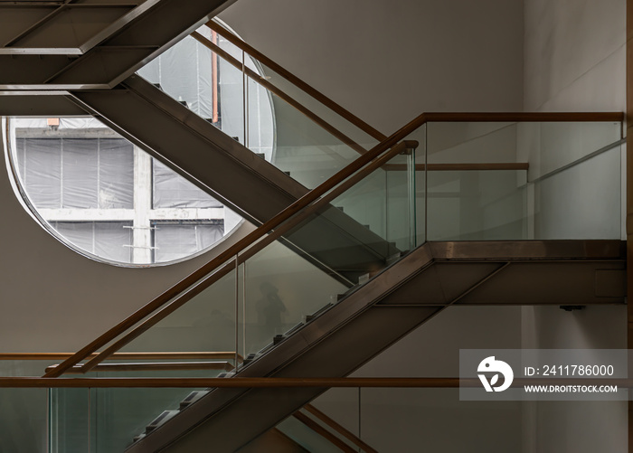 Side view of metal and glass stairs inside the building with sunlight shine through round window glass. Emergency exit by a stairwell in a Modern building. Selective Focus.