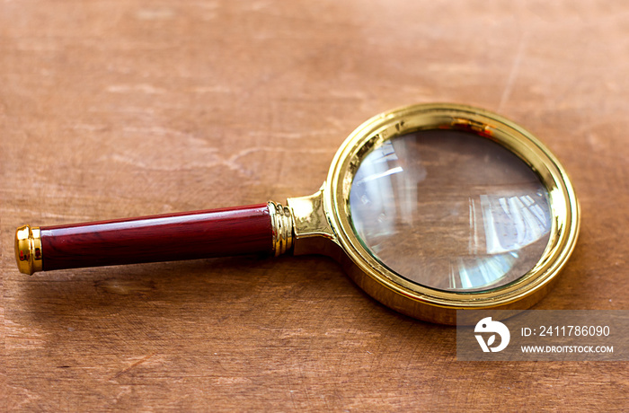 magnifying glass with sun glare on a wooden background, partial blur