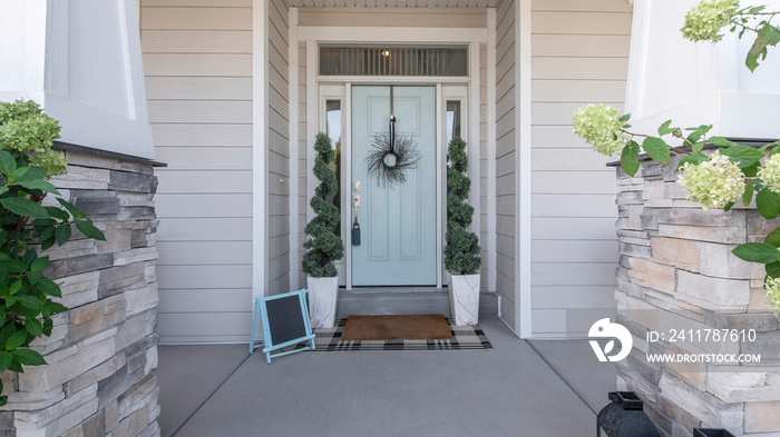 Pano Entrance of a house with decorative light blue front door and posts with stone bricks