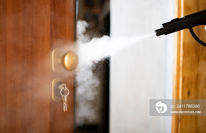 disinfection and sanitization with steam at home, steam flow is directed to the door handle and keys in the lock