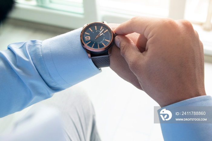 Businessman is checking time on his modern wrist watch. Top view