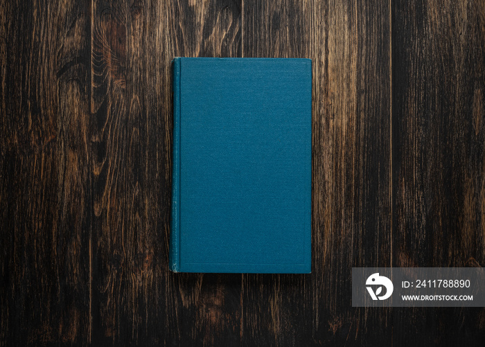 Closed book on vintage wooden background.  Old book on the wooden table. Closed book with empty cover laying on wooden table.