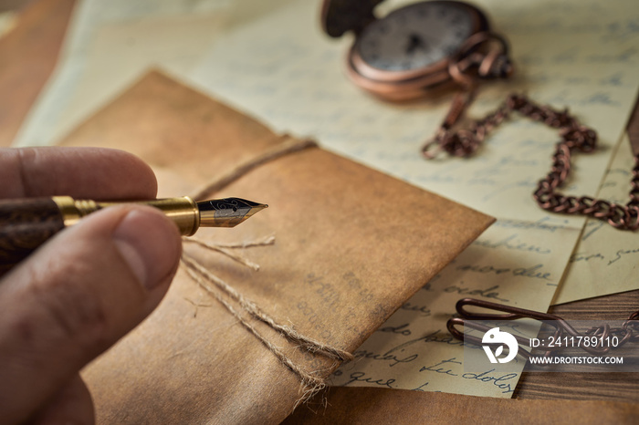 Vintage writing utensils on a wooden table, old watch, papers, letters, envelopes and scissors