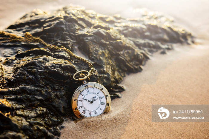 Vintage pocket watch on golden sand beach