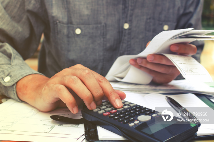 Man using calculator and calculating bills in home office.