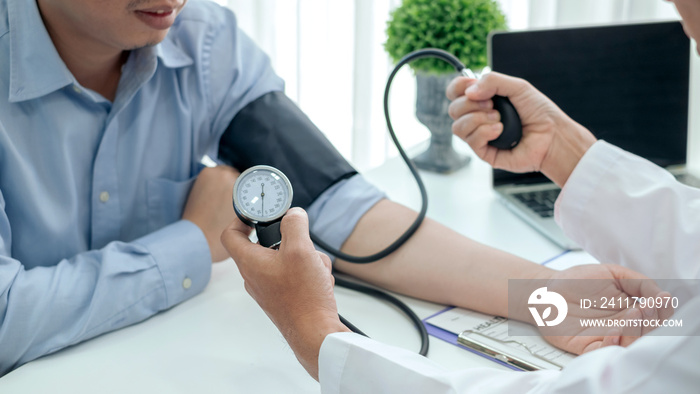 Doctor man is checking the blood pressure of the patient.