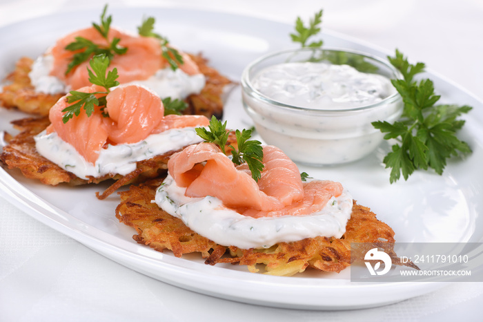 Crispy Potato fritters (a pancake, especially one made with grated potato) with cream cheese sauce with herbs and salmon