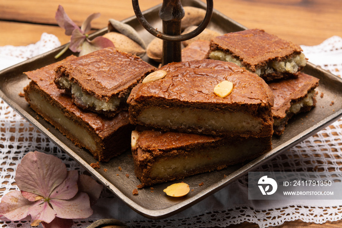 Fresh baked Dutch filled spicy cookies with almonds in autumn colors on dark wooden background