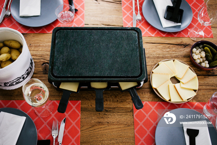 Swiss traditional dish called raclette including steamy potatoes, melted cheese and pickles eaten at christmas and wintertime