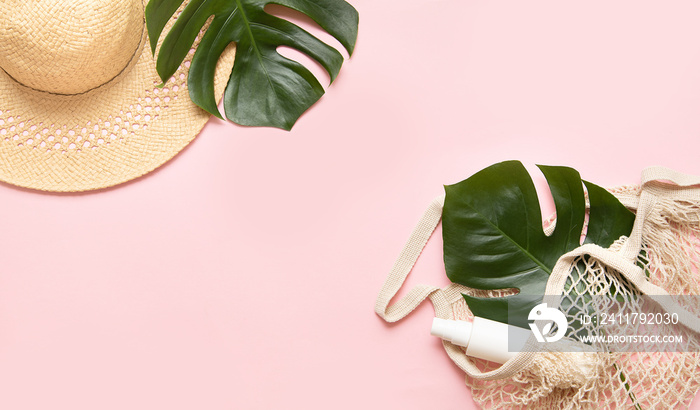 Tropical palm tree leaf and eco bag on a pink background. Sunscreen and hat in composition with monstera leaves.Vibrant minimal fashion concept