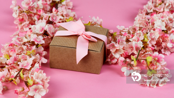 Front view of cherry blossoms and giftbox on a pink background for Mothers Day or Easter holiday