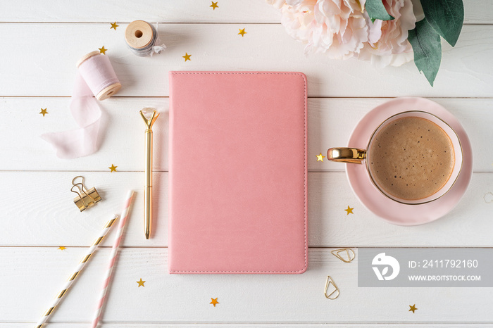 Top view of white working table background with blank paper notebook, cup of coffee. Flat lay peonies flowers, golden paper binder clips. Notepad and pen. Desktop mockup, workspace, stationery.