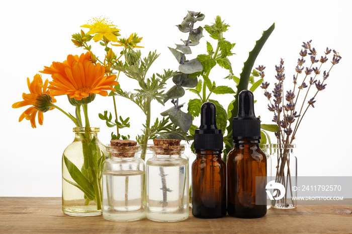 Essential oils with herbs and flowers on wooden table