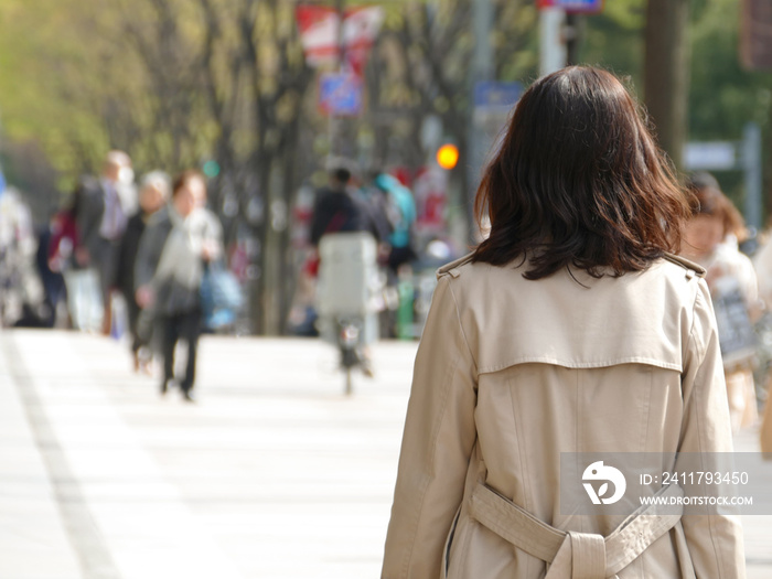 歩道に立つ若い女性の後ろ姿