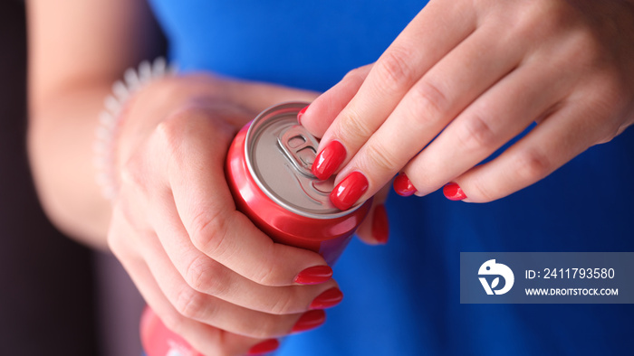 Woman with red manicure opening iron can with drink closeup