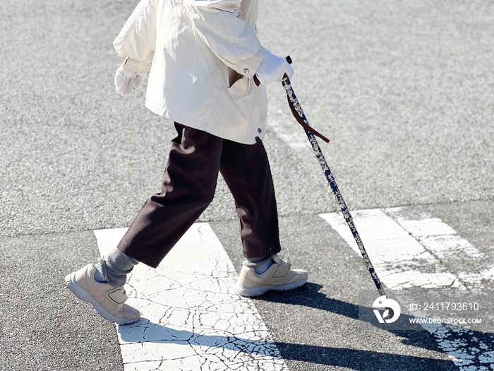 杖をついて横断歩道を元気に渡る高齢者の足元