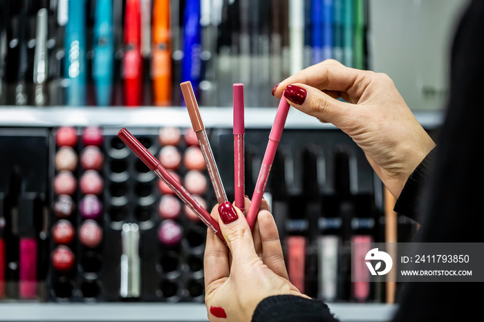 close-up seller hands demonstrating different eyeliners in beauty store