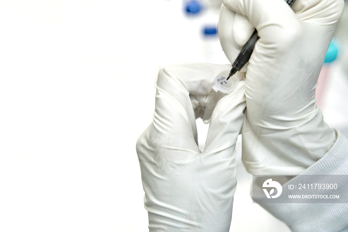 The woman researcher writing code cell passage on the micro tube to stock cell culture in the freezer.