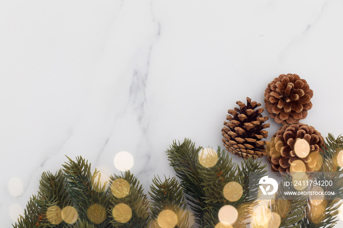 Christmas fir tree branches and bokeh blurred fairy lights on a marble background