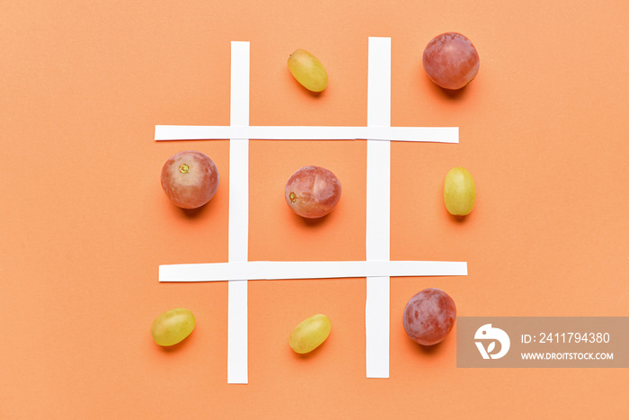 Game of Tic-tac-toe with ripe grapes on color background