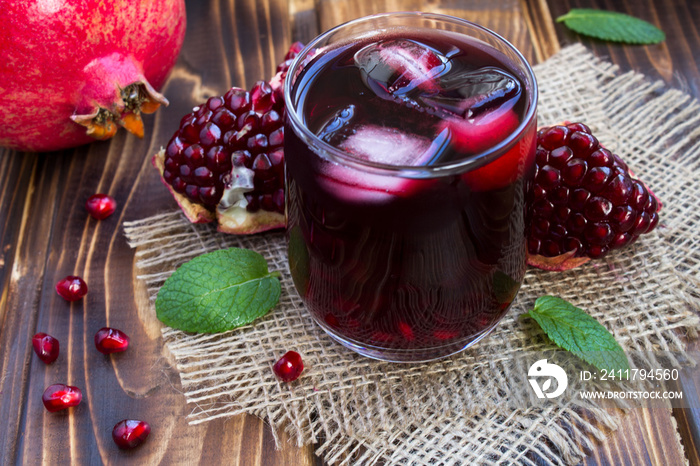 Pomegranate juice with ice in the glass on the rustic wooden background