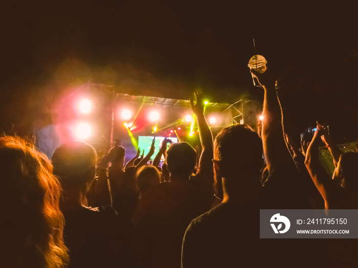 The party, concert concept. Crowd raising their hands and enjoying great rock festival. blur bokeh for background.