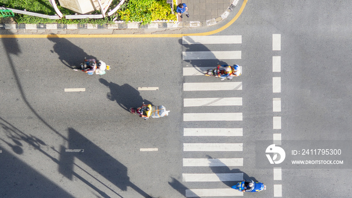 Top view aerial photo of a driving motorcycle on asphalt track and pedestrian crosswalk in traffic road with light and shadow silhouette