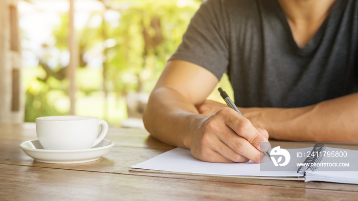 Man writing on a notebook in a cafe.