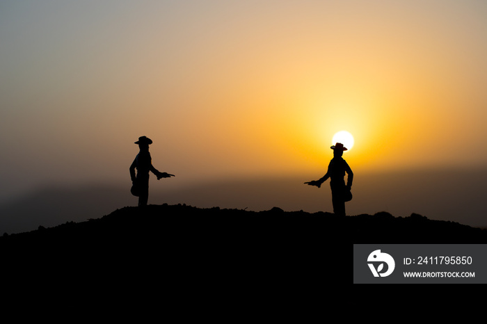 Cowboy concept. Silhouette of Cowboys at sunset time. A cowboy silhouette on a mountain with an yellow sky.