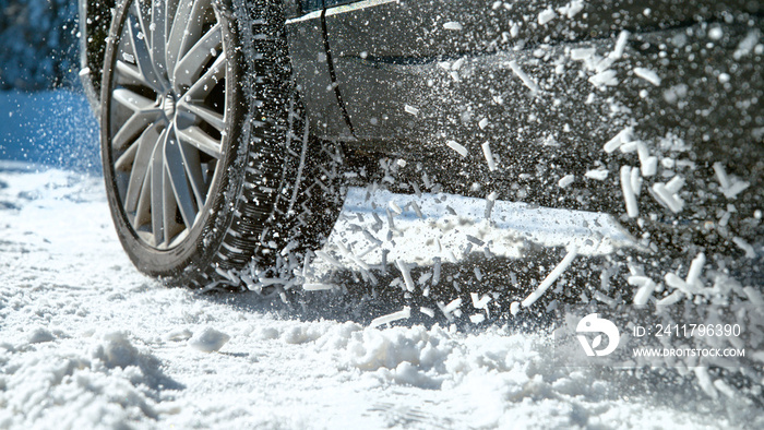 CLOSE UP: Powerful car’s wheels spin in place and spew up pieces of white snow.