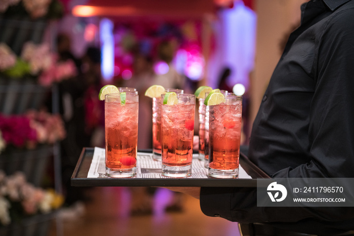 Refreshing alcohol red cocktails with ice and lemon on waiter plate on evening event party