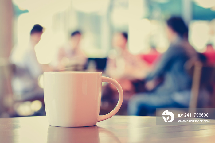 Coffee cup on the table with people in coffee shop as blur background - vintage (retro) style color effect