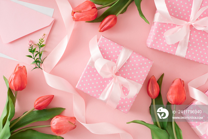 Woman day mood concept. Top view photo of present gift boxes with silk ribbon bows and tulips flowers on pastel pink background.