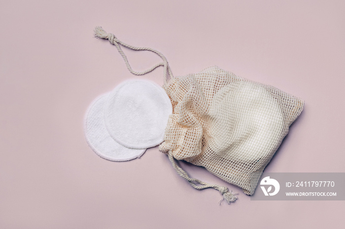 Reusable Bamboo Cotton Makeup Remover Pads in net bag on pink background. Zero-waste, sustainable lifestyle concept.