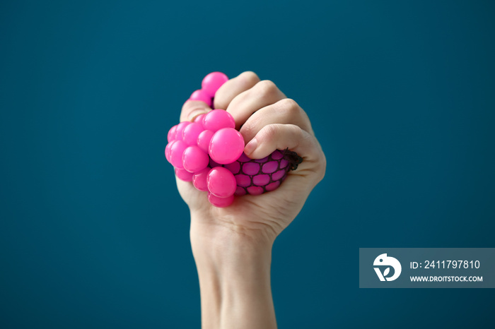 Female hand squeezing stress ball on color background