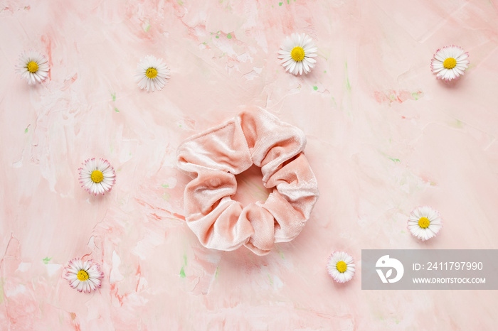 Pink velvet scrunchie and fresh spring flowers on pastel backround. Flat lay, top view. Diy accessories, hairstyle, lifestyle, spring and summer outfit ideas concept, copy space