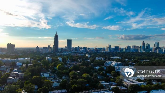 a stunning aerial shot of the cityscape at sunset with skyscrapers surrounded by blue sky and powerful clouds and lush green trees in Atlanta Georgia USA