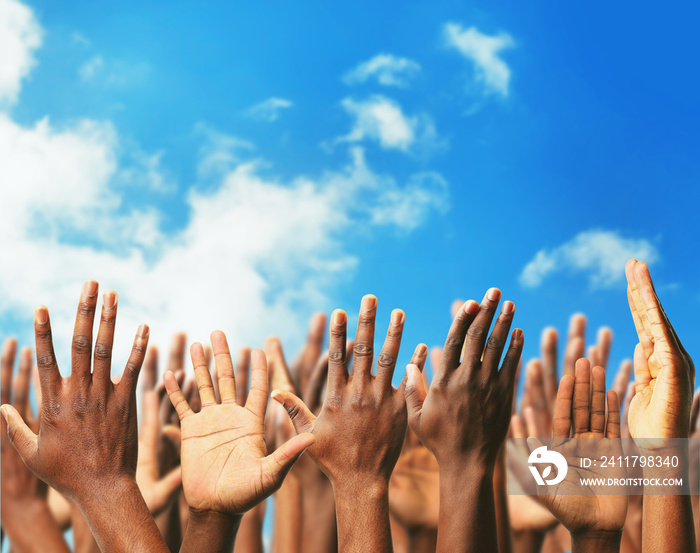 Crowd raising hands on blue sky background