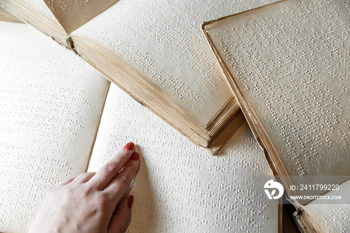 woman reading braille text on old book